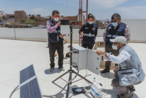 A group of people implementing disaster risk reduction measures around a solar panel on a roof.