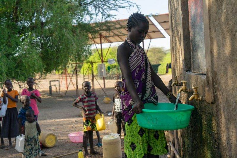 A woman is accessing energy to fill a bucket with water.