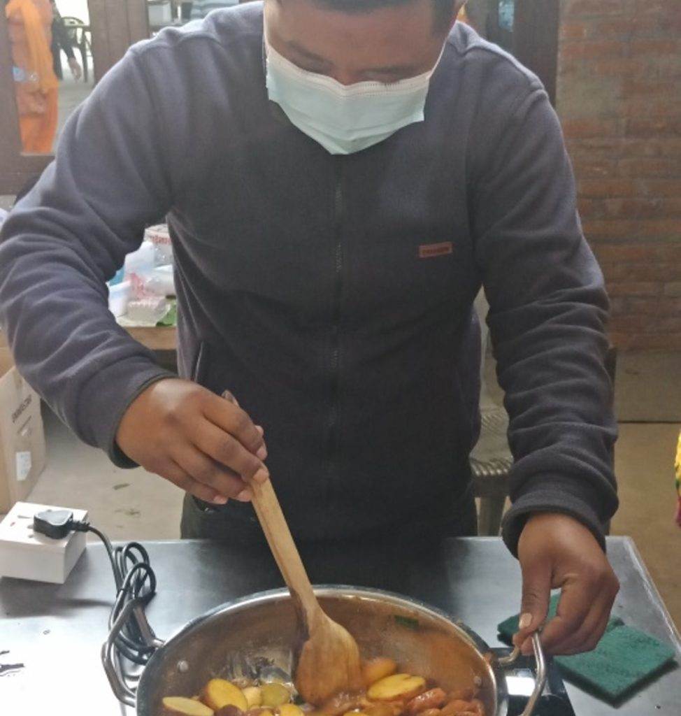 A man in Nepal cooking food in an electric pan.