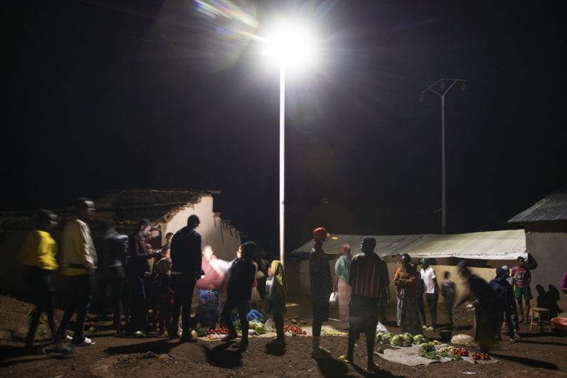 A group of people gathering around a street light during the Practical Action at the Humanitarian Energy Conference & Sustainable Energy for All Forum 2022.