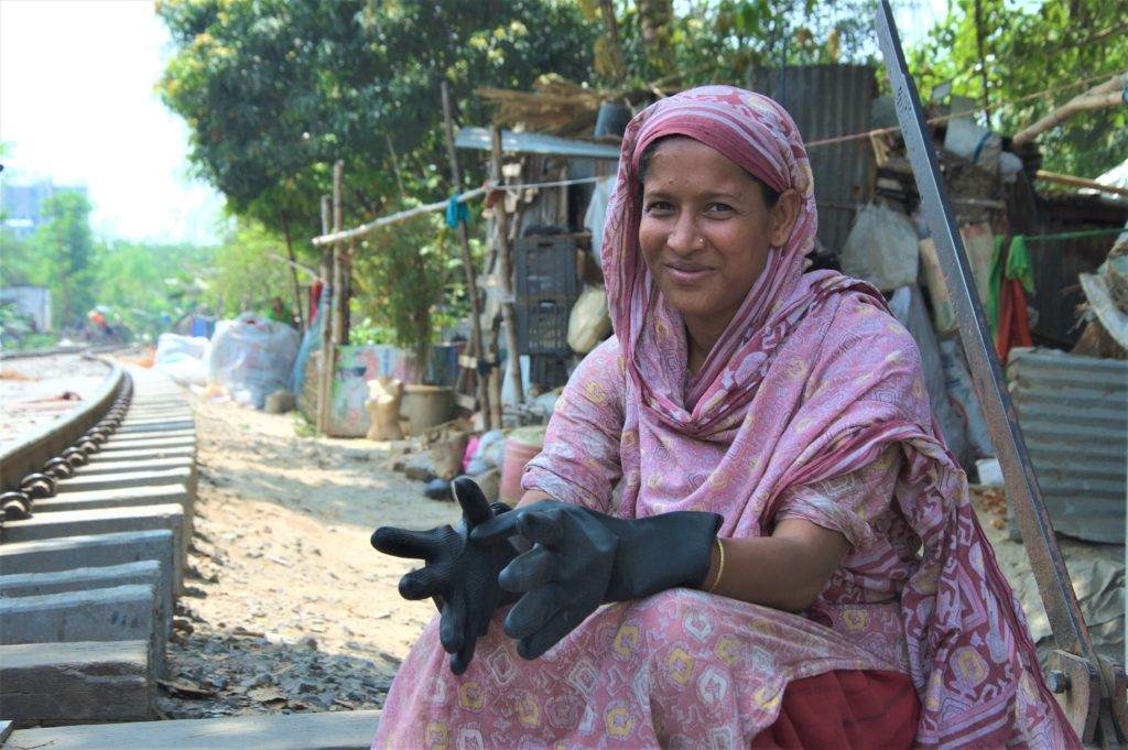 A woman in a sari recycling plastic on a train track in Bangladesh.