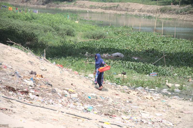 A woman walking along a river in Faridpur, the front line of the global waste crisis.