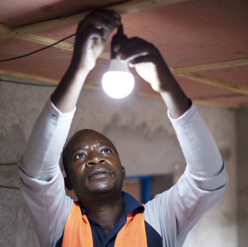A man showcasing innovative practical action with a light bulb at the Sustainable Energy for All Forum 2022.