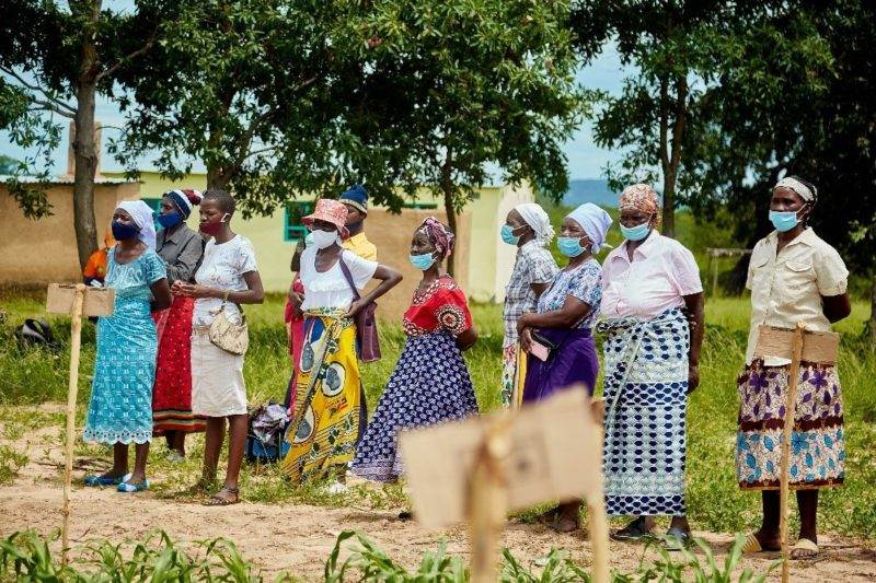 A group of Rwandan women farmers wearing face masks in a field stand up to climate change.