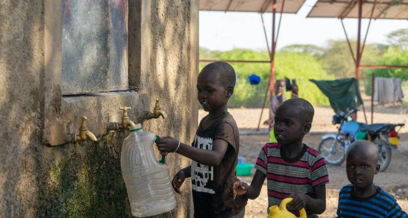 A group of young boys standing next to a water spigot in Turkana.