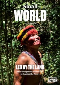 An Indigenous person wearing a colourful headdress and traditional attire stands in a sunlit forest, looking upward. The magazine cover reads: 