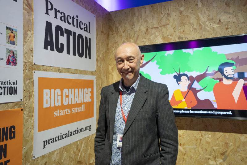 A man in a suit standing in front of a big change sign at COP27.