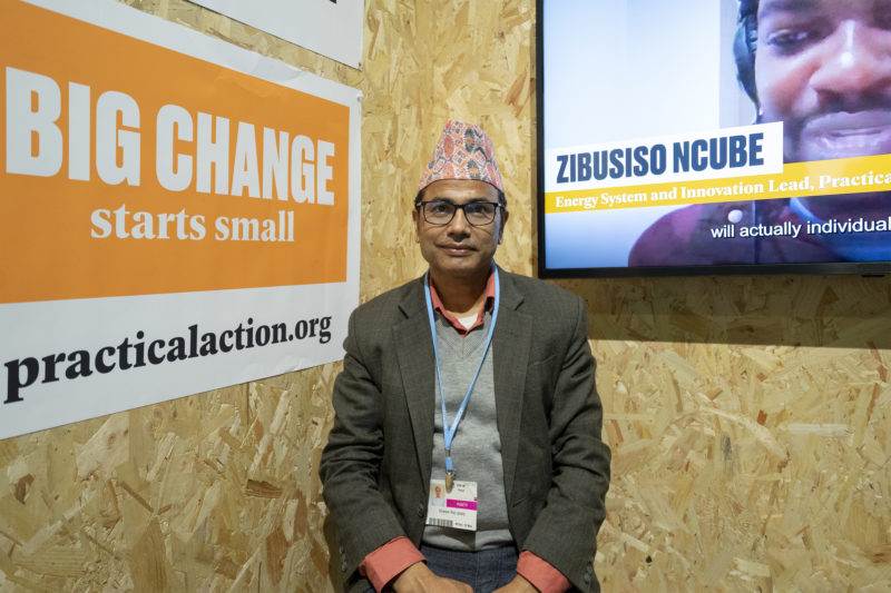 A man in a hat standing in front of a television at Practical Action at COP27 - Sharm El-Sheikh 2022.