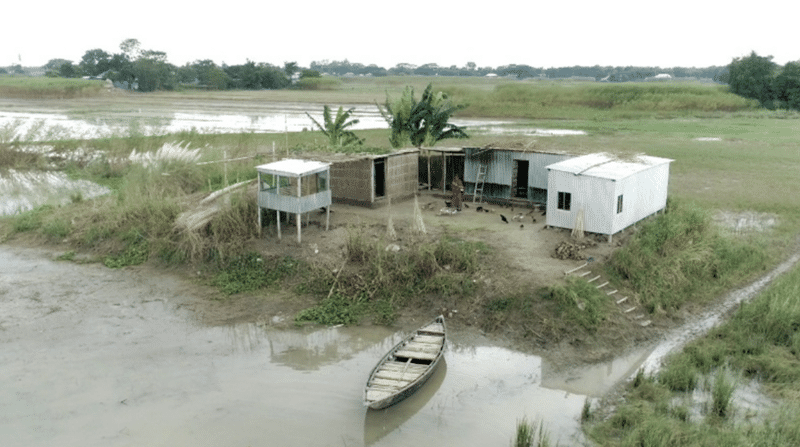 An aerial view of a small house in a flooded area, showcasing effective partnerships in flood vulnerable communities.