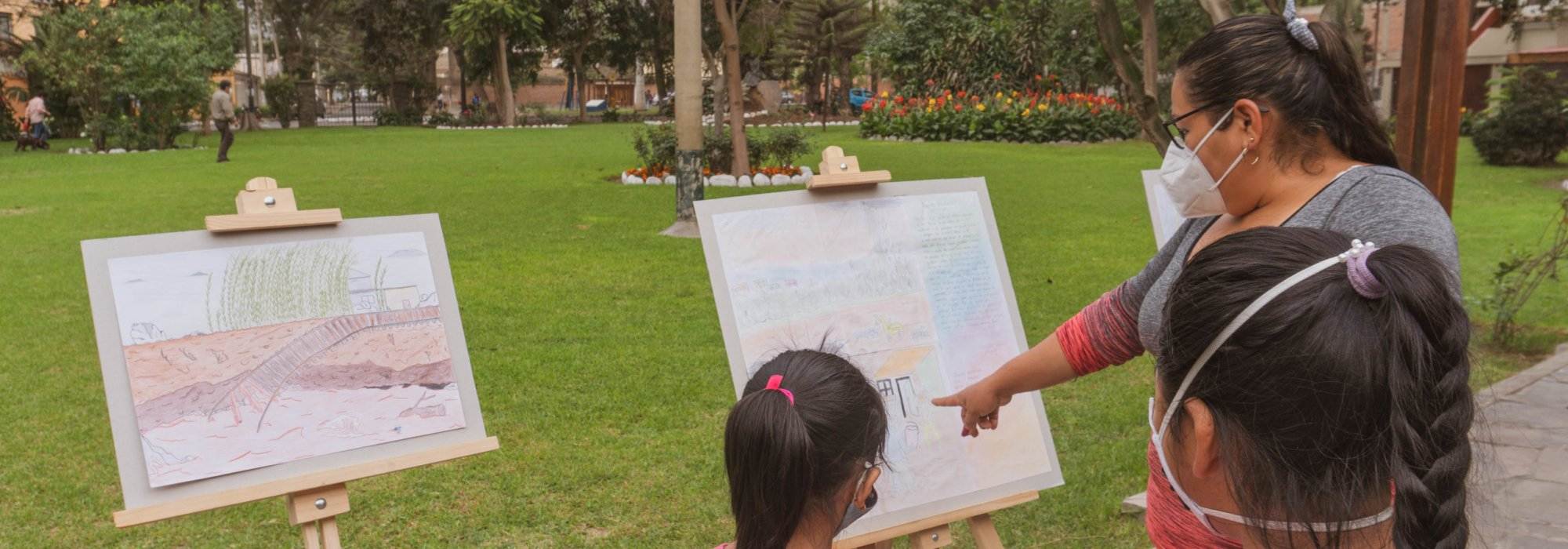 Peruvian lady looking at art work with two young artists