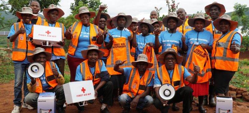 A group of Zimbabweans in orange vests posing for a photo, showcasing their better preparation for climate impacts.