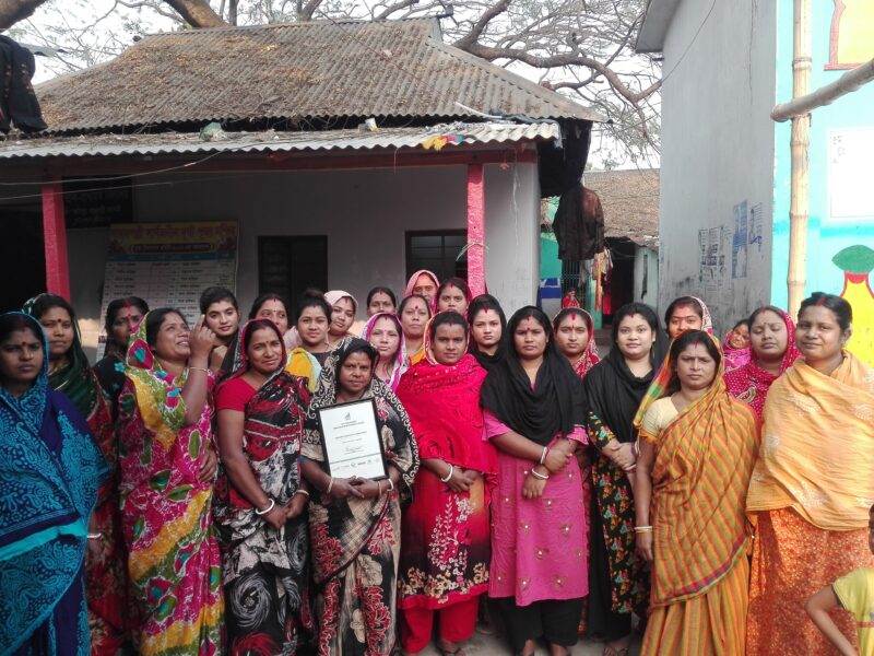 A group of women implementing faecal sludge management practices in front of a house.