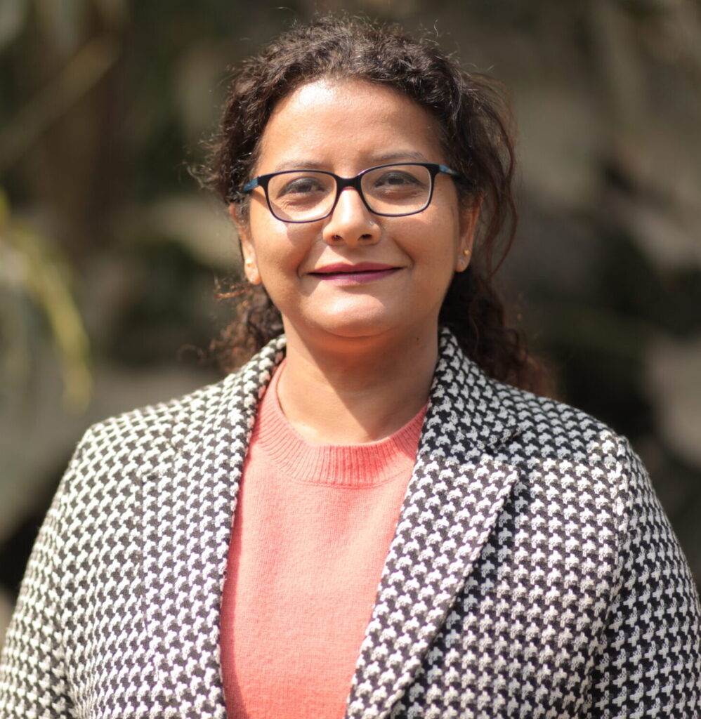A profile shot of a woman wearing glasses and a blazer.