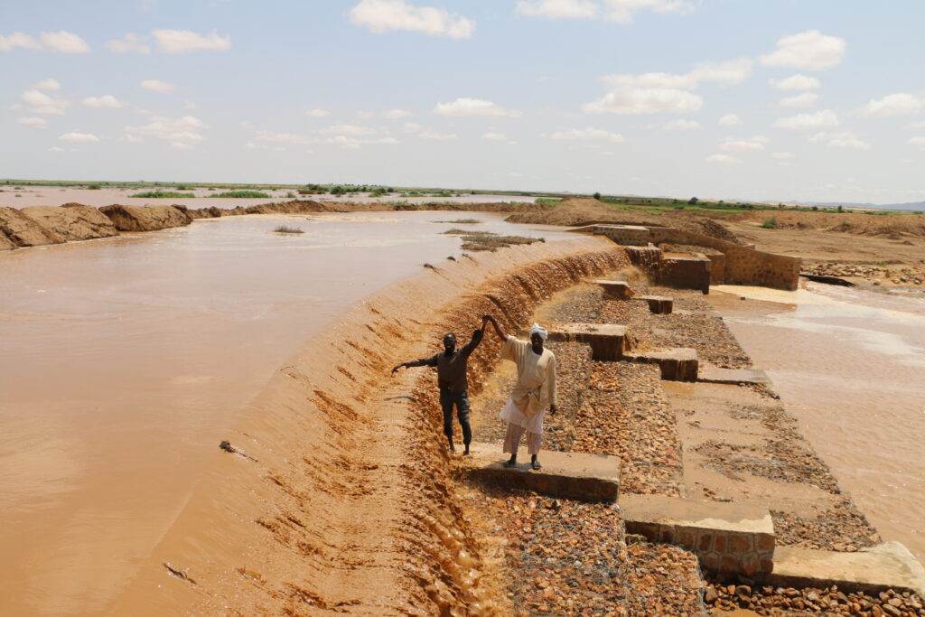 A man is standing next to a muddy river, igniting big change by turning the tables on climate change.