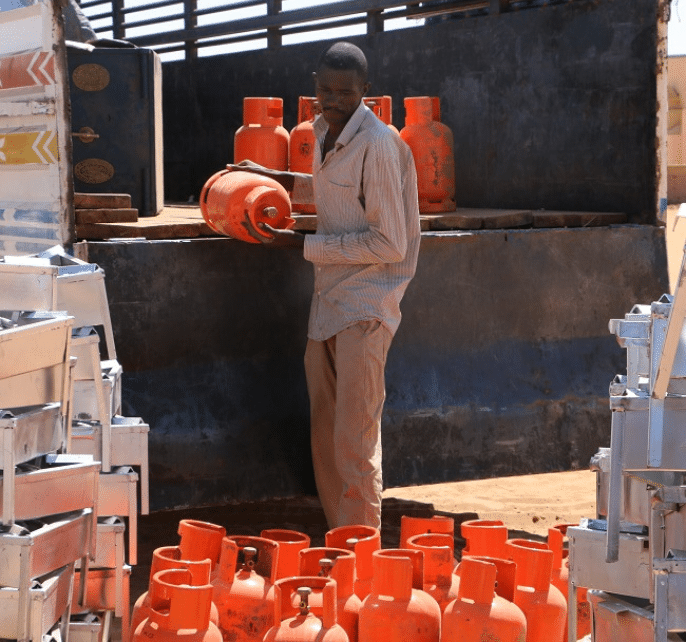 A man overseeing a truck filled with orange gas cylinders for clean cooking.