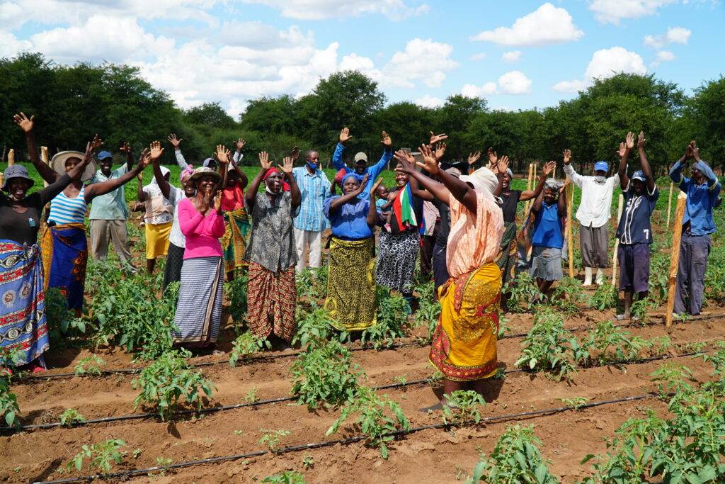 A group of people standing in a field with their hands raised.