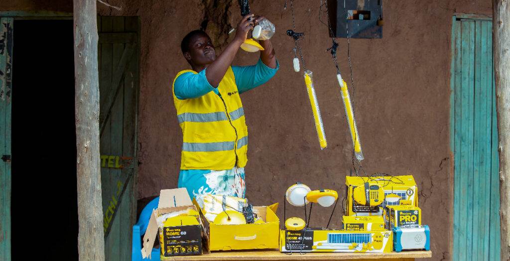 A woman in a yellow vest is working on a ladder.