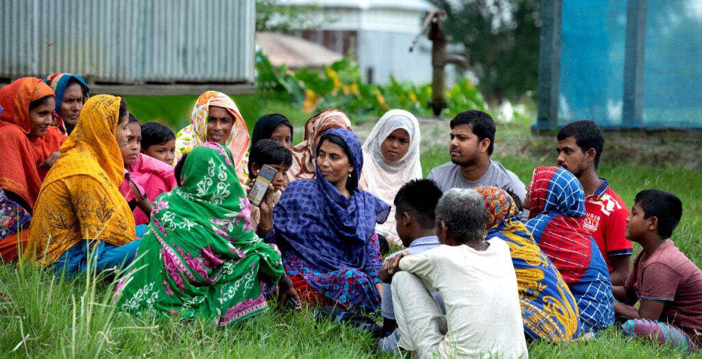 A group of people sitting in the grass.