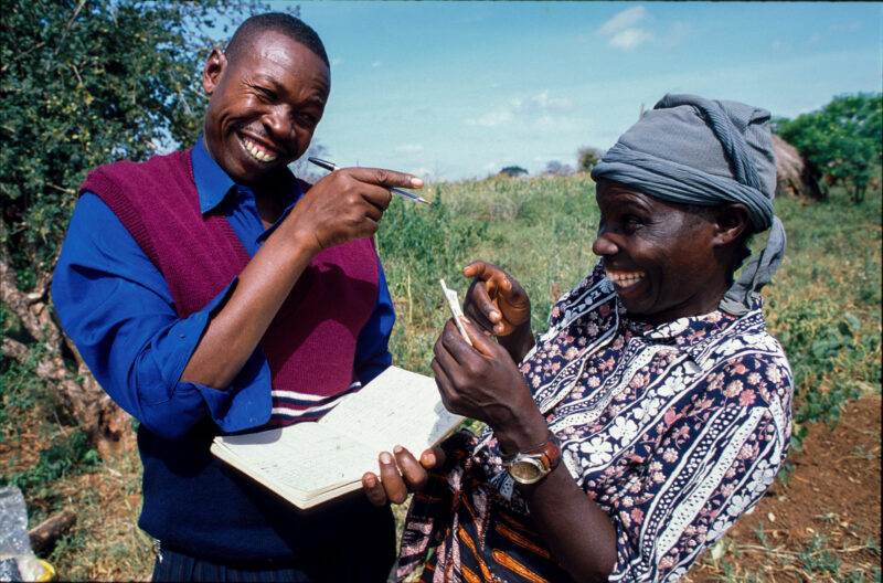 A couple in a field holding a piece of paper, showcasing the enduring beauty of simplicity.