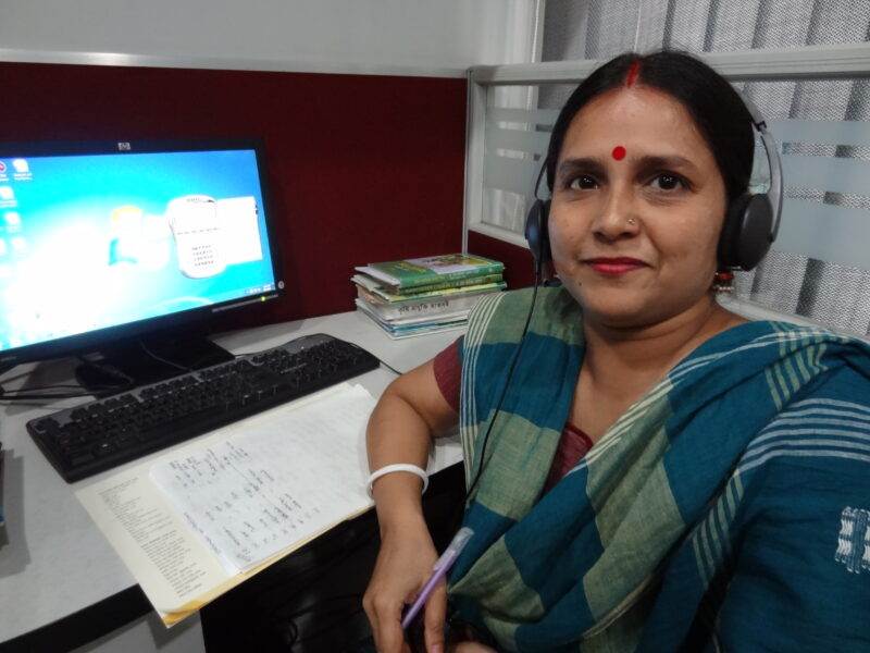 A woman in a sari, representing the beauty of small communities, sitting in front of a computer.