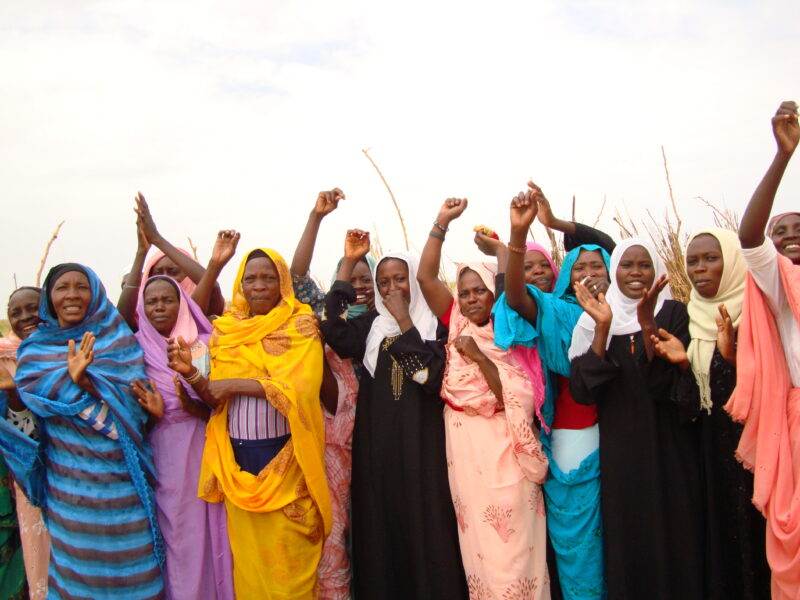 A small group of women with their hands in the air, half a decade on.