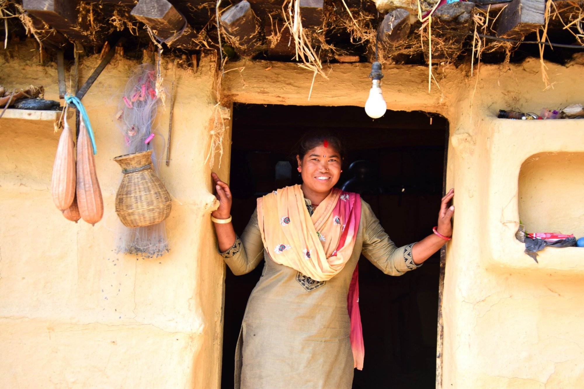 A woman standing in the doorway of a Practical Action mud hut in Nepal.