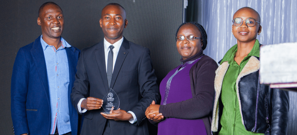 A group of people posing for a photo with an award won by Practical Action in Zimbabwe.