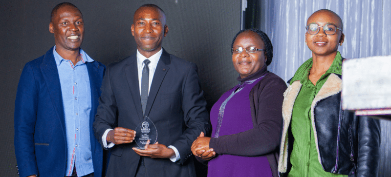 A group of people posing for a photo with an award won by Practical Action in Zimbabwe.