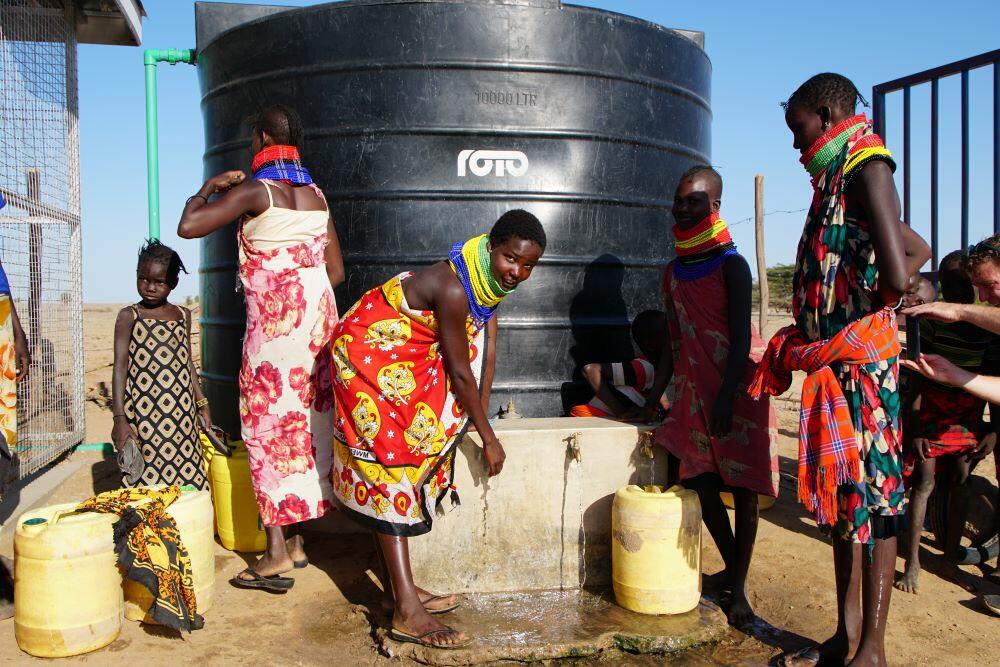 A group of people standing around a water well.
