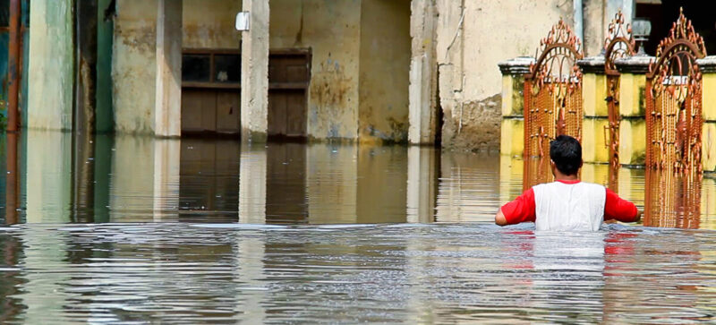 A resilient man wading through a flooded street with determination, embodying the power of hope in action.