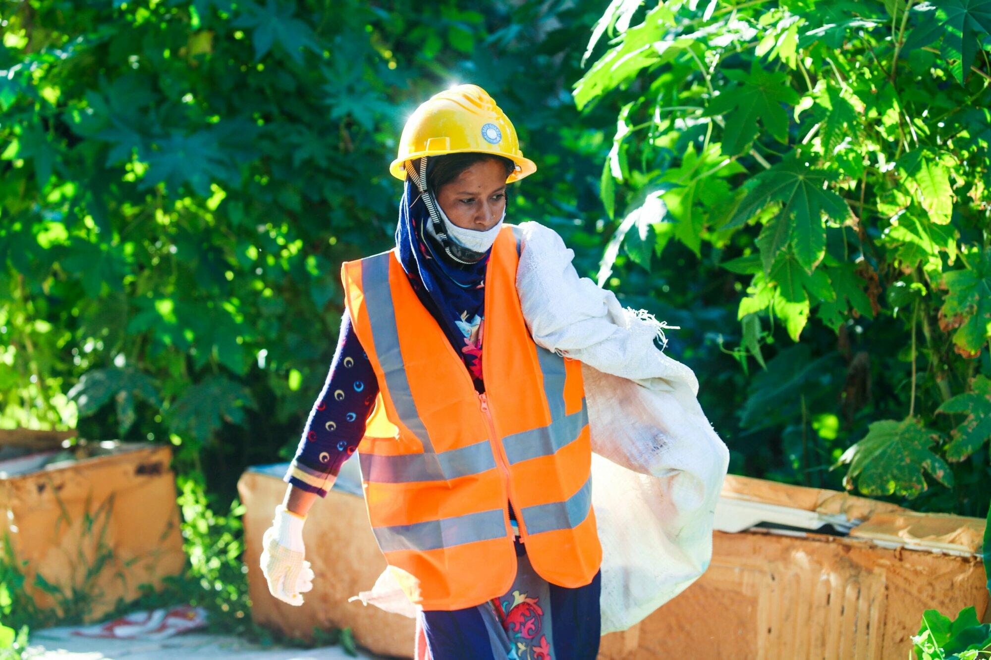 A woman in practical action wearing a safety vest and carrying a bag in Sudan.