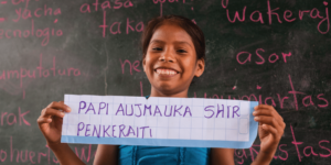 A young girl holding up a sign that reads par aumaka shir, radiating Stories of Hope.
