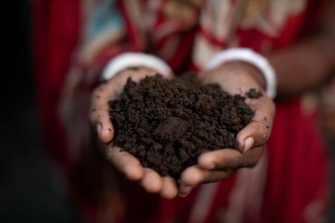 Growing hope: A woman holds a pile of dirt in her hands, showcasing the life-saving impact of worms in Bangladesh.