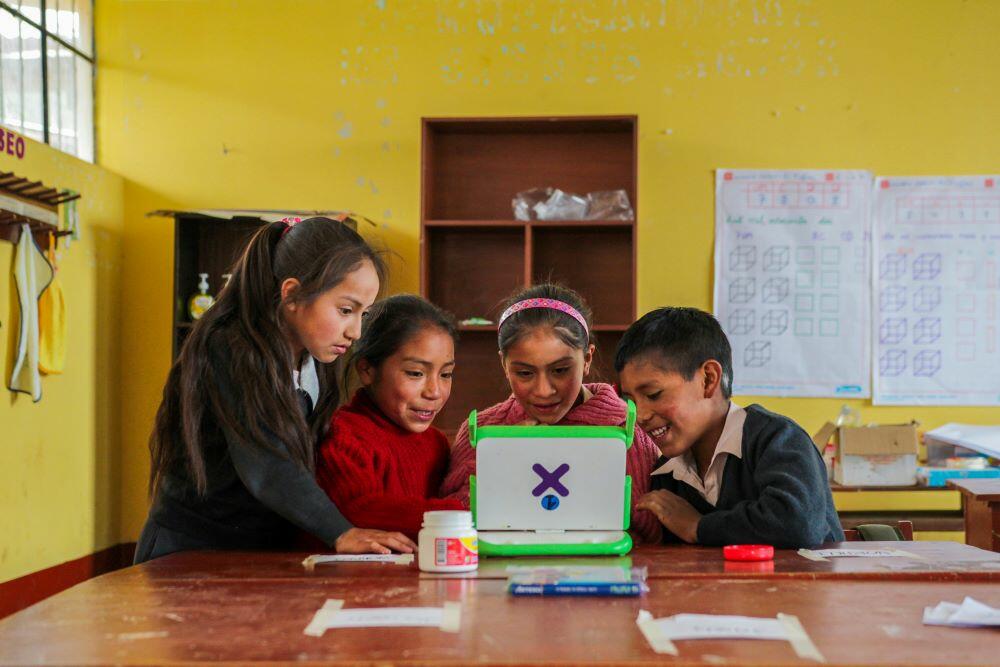 Practical Action en Peru - A group of children utilizing a laptop in a classroom.