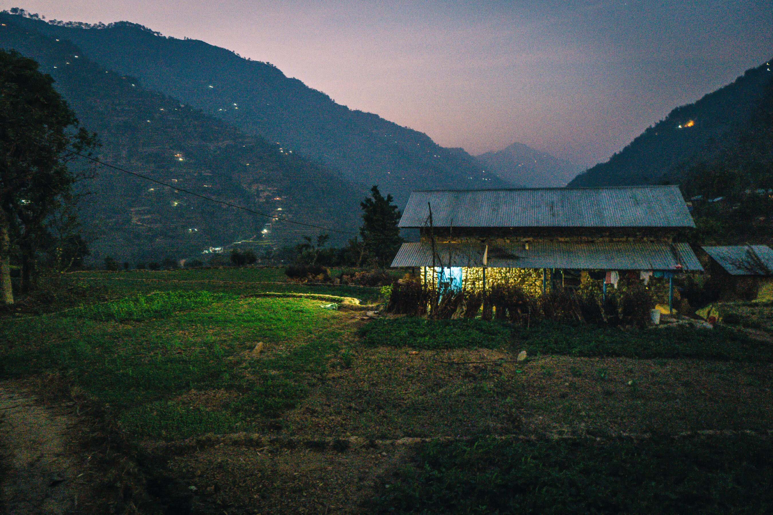 A house in the middle of a field at dusk, exemplifying extreme poverty.