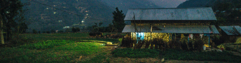 A house in the middle of a field at dusk, exemplifying extreme poverty.