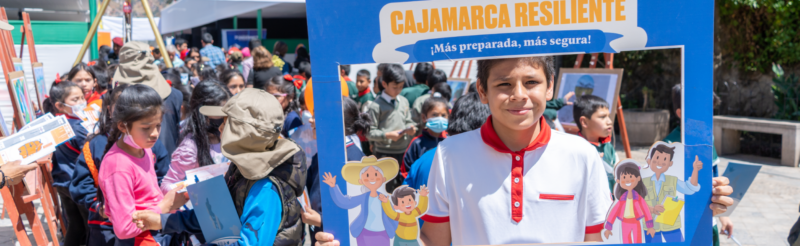 A group of children holding up a sign with a picture of a child, fostering resilient communities in Peru (BHA).