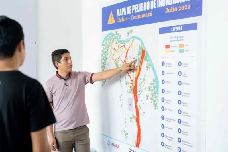 Two resilient men standing in front of a wall with a map of Peru.