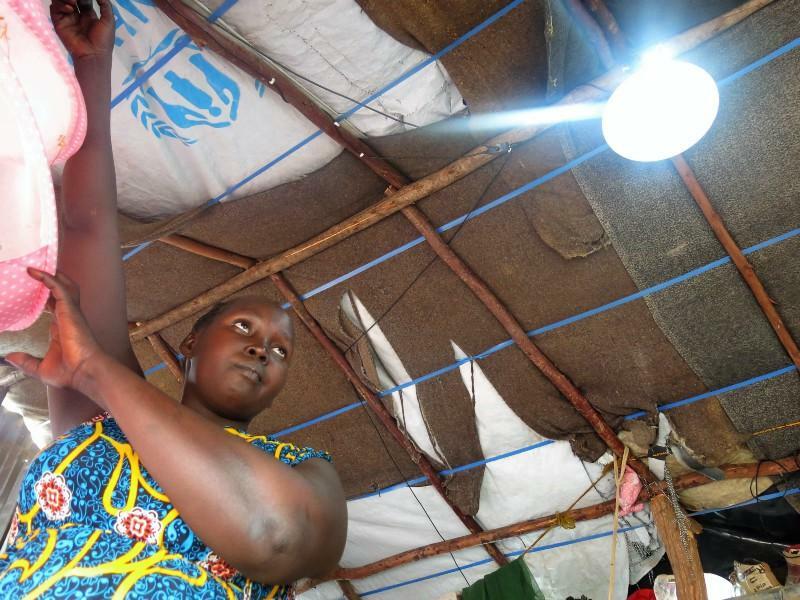 A woman hanging a light from a tent.