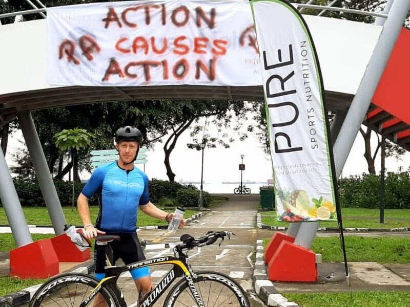 A man standing in front of a sign that says action causes action.