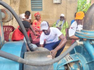 A group of people in West Africa fervently working on a water pump, driven by hope for a better future.