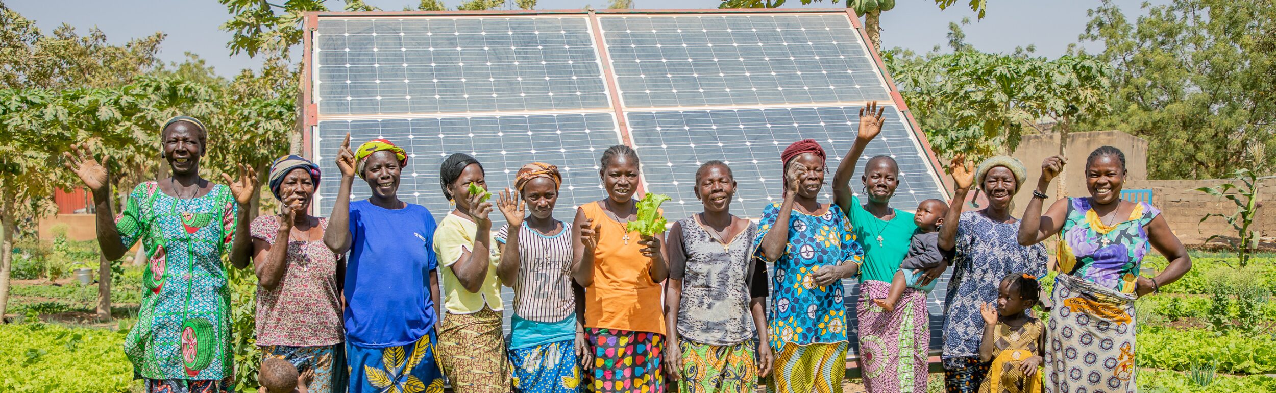 A group of happy farmers in front of a solar panel.