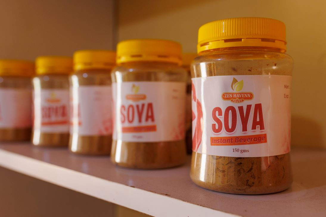 Four plastic jars of Zen Haven Soya Instant Beverage with yellow lids are lined up on a shelf, with the front jar in clear focus.