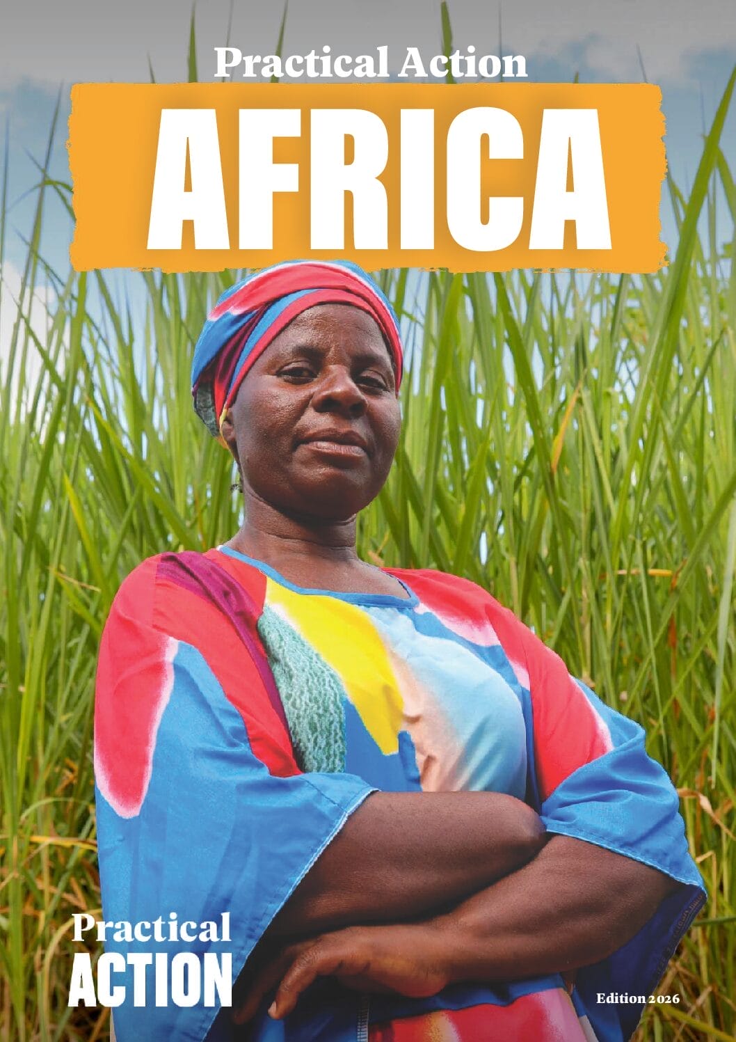A confident woman in a colourful dress and headwrap stands with folded arms in front of tall green grass. The magazine cover reads "Practical Action AFRICA," with "Edition 2026" in the corner.